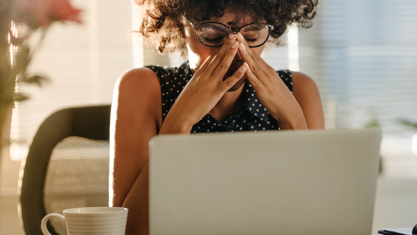 A person at a desk in a moment of tension, hand briefly to their forehead, captured mid-task.